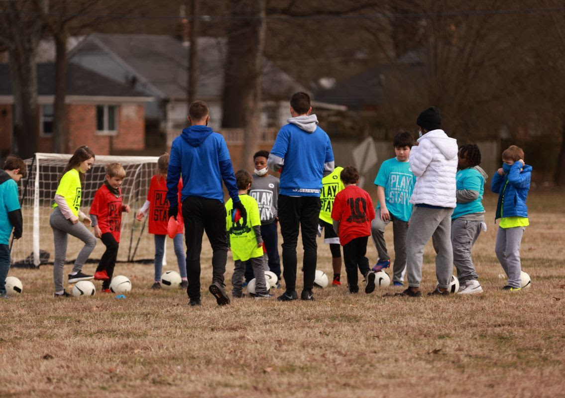 players and coaches dribbling soccer ball on the field